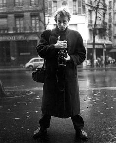 a man standing in the rain holding a camera