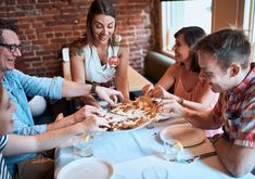 a group of people sitting around a table eating pizza