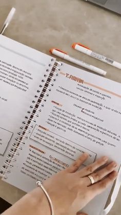 a person is writing in a notebook with two pens