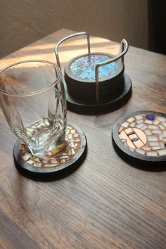 three coasters on a wooden table with glass cups and saucers in the middle