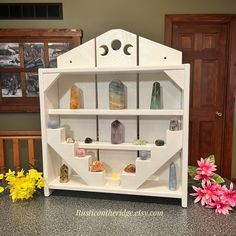 a shelf that has some rocks in it on top of a table next to flowers