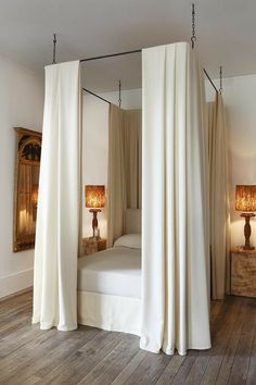 a canopy bed with drapes hanging from it's sides