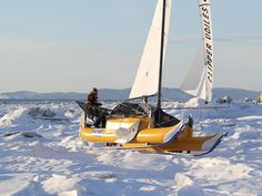 a small yellow sailboat in the middle of some ice covered water with people standing on it