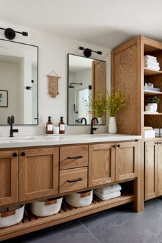 a bathroom with wooden cabinets and white towels on the counter top, along with two large mirrors