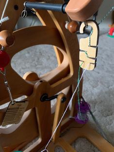 a close up of a wooden spinning wheel with beads and wood pegs on it