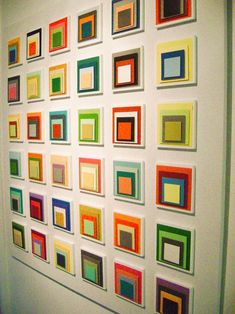 a wall with many square and rectangle paintings on it's sides, all in different colors