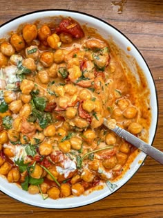 a white bowl filled with chickpeas and spinach on top of a wooden table