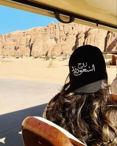 two people sitting on a bus looking out the window at mountains and desert in the distance