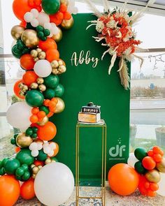 an orange, white and green balloon arch with balloons