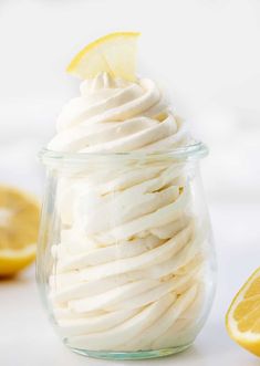 a glass jar filled with whipped cream next to sliced lemons on a white surface