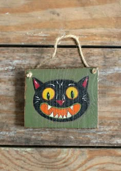 a wooden sign with a black cat painted on it