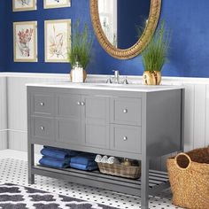 a white bathroom vanity with blue walls and pictures on the wall above it, along with a large round mirror