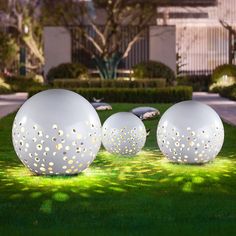 three large white balls sitting on top of a lush green field next to each other