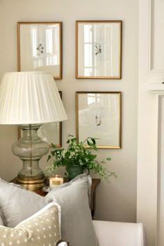 a living room with pictures on the wall and a lamp next to it, in front of a couch