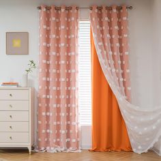 an orange and white curtain hanging in front of a window with polka dots on it