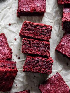 red velvet brownies cut into squares and placed on parchment paper with crumbs