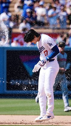 a baseball player standing on top of a field in front of a crowd and spraying water