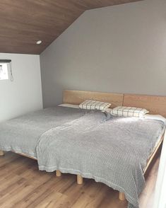 a bed sitting inside of a bedroom on top of a hard wood floor next to a window