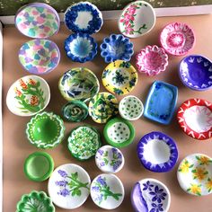 many different colored bowls and plates on a table top with flowers painted all over them