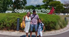 a man and two children standing in front of a sign for gardens by the bay