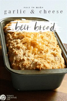 a loaf of beer bread sitting in a pan on top of a wooden table with the words garlic and cheese bee bread