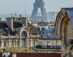 the eiffel tower is in the distance behind some buildings with roofs and windows