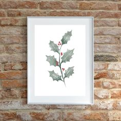 a painting hanging on a brick wall next to a white frame with holly leaves and red berries