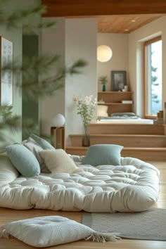 a living room filled with lots of furniture and pillows on top of wooden flooring