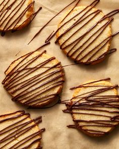 some cookies with chocolate drizzled on top of each one and sitting on a piece of parchment paper