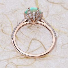 an opal and diamond engagement ring on a marble surface with the center stone surrounded by small diamonds