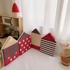 three houses made out of cardboard sitting on top of a bed next to a basket