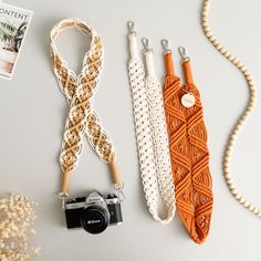 three different types of necklaces and a camera on a white table with beads, flowers and a book