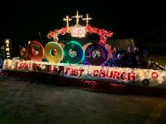 a parade float with lights and decorations on it's side in front of a church