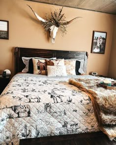 a bedroom with a large bed covered in blankets and pillows, deer heads on the wall