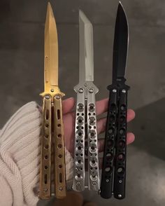 a person holding four different types of knifes in their hands, one is gold and the other is black