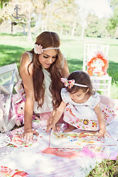 a woman and her daughter are sitting on the grass