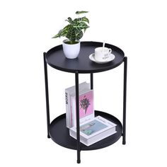 a black round table with a plant on top and books next to it, against a white background