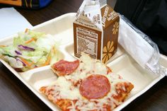 a slice of pepperoni pizza and salad on a paper plate with a carton of milk