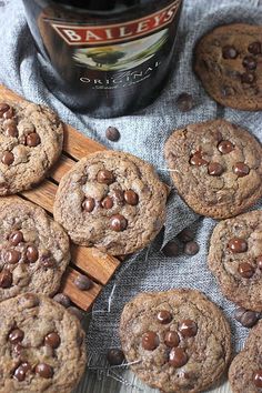 chocolate chip cookies on a wooden board next to a bottle of beer