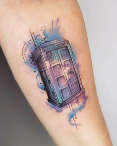 a watercolor painting style tattoo on the arm of a woman's leg with a blue and purple tardish