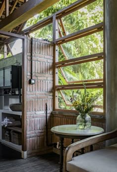 a table and chair in a room with wooden beams on the ceiling, next to an open window