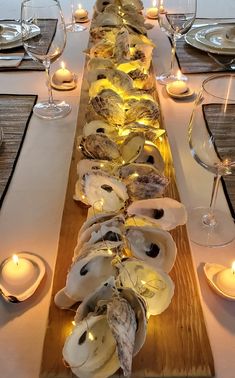 a long wooden table topped with lots of plates and glasses filled with water next to candles