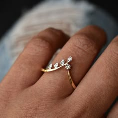 a woman's hand wearing a gold ring with three small white diamonds on it