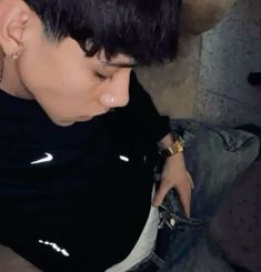 a man with black hair and piercings sitting on a couch