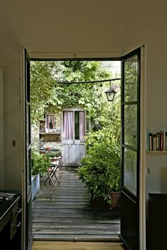 an open door leading to a kitchen and dining area with potted plants on either side