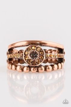 A smooth and dotted copper band flank a topaz rhinestone encrusted band, creating glittery layers across the finger. Encrusted in golden topaz rhinestones, a circular frame is pressed into the center of the bands for a refined finish. Features a dainty stretchy band for a flexible fit. Sold as one individual ring. Gold Copper Round Ring, Gold Topaz Crystal Ring, Adjustable Gold Crystal Ring With Bling, Adjustable Gold Crystal Bling Ring, Gold Rings With Rhinestones, Adjustable Bedazzled Gold Jewelry, Elegant Gold Bedazzled Jewelry, Gold Copper Anniversary Rings, Brown Rings