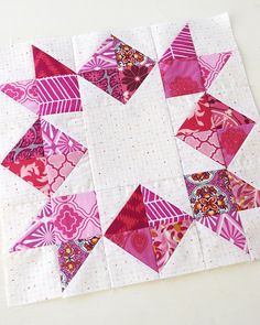 a pink and white patchwork quilt on top of a table