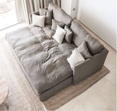 a large gray couch sitting on top of a living room floor next to a window