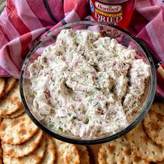 a glass bowl filled with dip surrounded by crackers