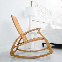 a wooden rocking chair sitting in front of a white bed next to a night stand